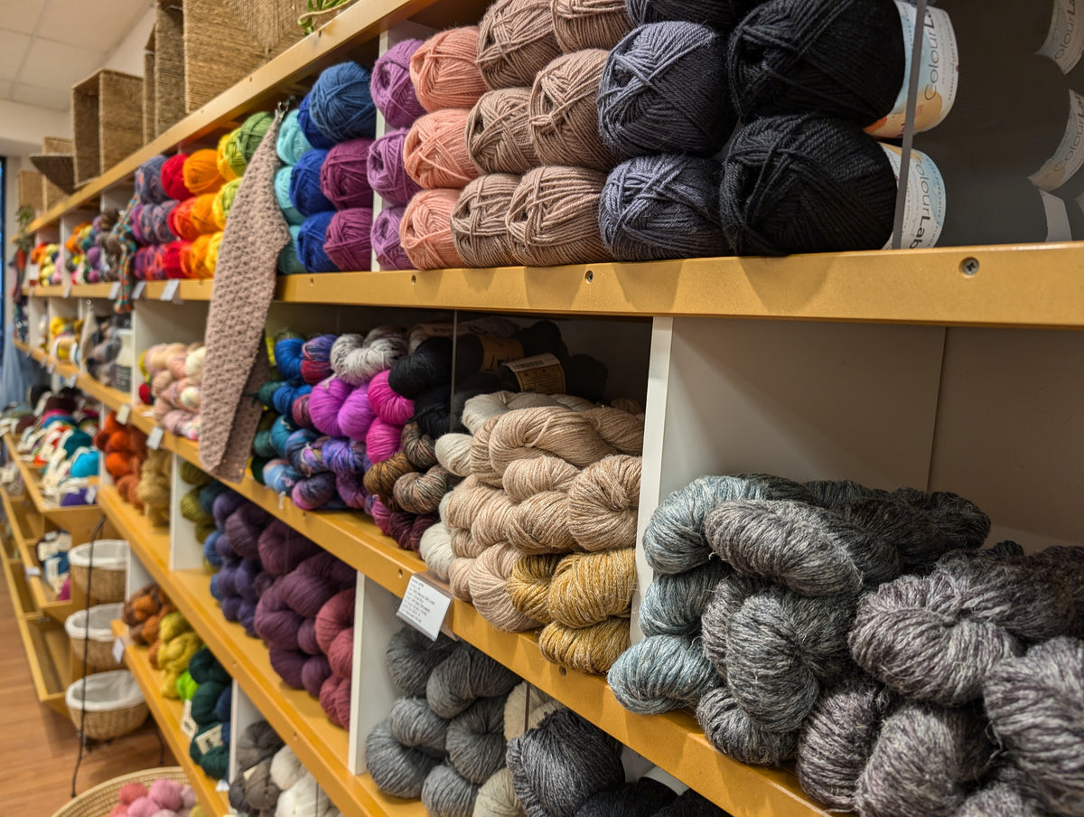 Closeup photo of a long shelf full of colorful yarn.